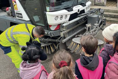 un groupe de jeunes agés d'environ 10 ans observe un agent de la propreté urbaine leur expliquer l'importance du tri des déchets. - Agrandir l'image, fenêtre modale