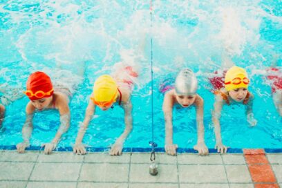 Des enfants dans une piscine sont accrochés au rebord et apprennent à battre des pieds sous l'eau. - Agrandir l'image, fenêtre modale