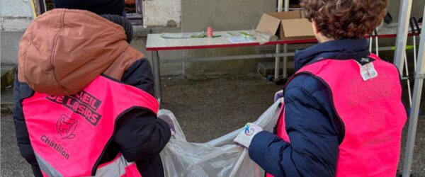 Deux enfants tiennent un sac poubelle. Ils portent le gilet rose des accueils de loisir châtillonnais.