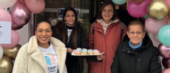 Quatre femmes d'ages différents se tiennent autour de macarons. Autour d'elle, il y a une arche de ballons.