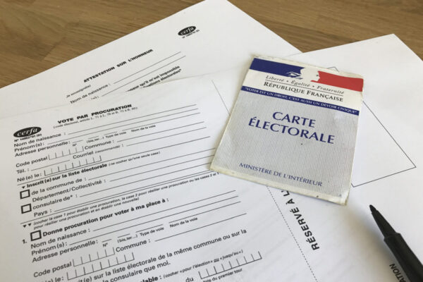 Une carte d'électeur posée sur le formulaire de procuration avec un stylo.