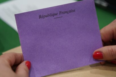 Gros plan sur un bulletin de vote violet portant la mention « République Française », tenu entre deux mains, lors du scrutin organisé pendant la séance d’installation du Conseil municipal. - Agrandir l'image, fenêtre modale