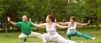 Trois personne pratiquent le tai chi dans un parc
