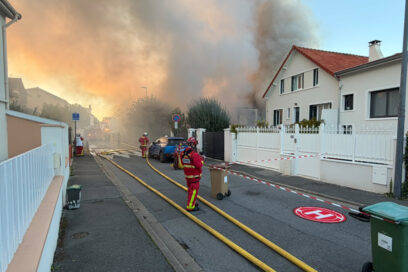 Des sapeurs-pompiers interviennent dans une rue de Châtillon, envahie par une épaisse fumée à la suite d’un incendie dans l’ancienne école Jean-Jaurès. Des tuyaux d’incendie sont déployés sur la chaussée et un périmètre de sécurité a été installé. - Agrandir l'image, fenêtre modale
