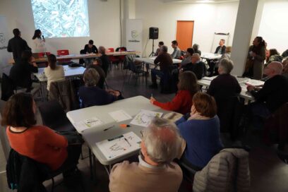 Réunion du comité d’urbanisme de la Ville de Châtillon. Des habitants et participants sont réunis autour de plusieurs tables pour échanger autour d’un projet d’aménagement présenté sur écran lors d’un atelier participatif. - Agrandir l'image, fenêtre modale