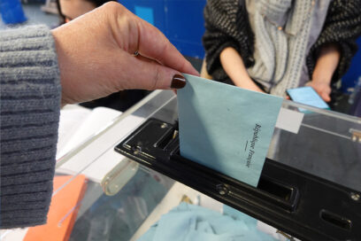 Un électeur qui glisse une enveloppe dans l'urne électorale. - Agrandir l'image, fenêtre modale