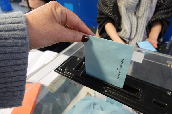 Un électeur qui glisse une enveloppe dans l'urne électorale.