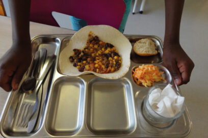 Un enfant tient un nouveau plateau en inox pour son repas. - Agrandir l'image, fenêtre modale