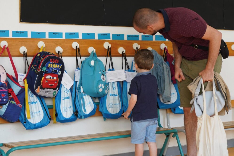 Un enfant et son papa devant les sacs de la rentrée scolaire, dans une école de la ville.