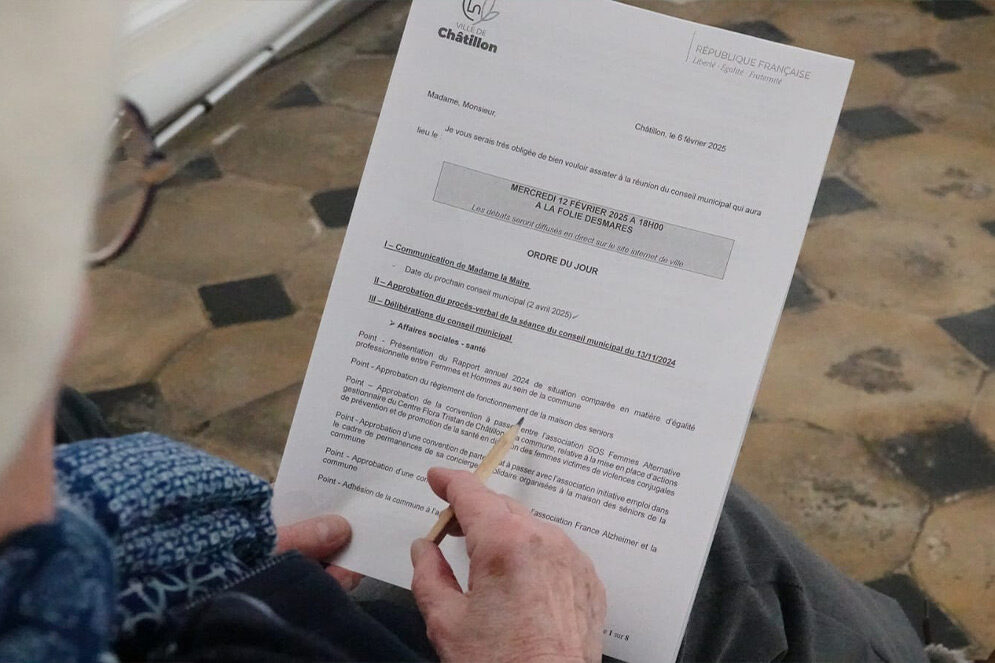 Une Châtillonnaise assistant à la séance du mercredi 12 février 2025 du Conseil municipal, qui tient dans sa main l'ordre du jour de la séance.