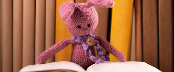 Une peluche mignone qui lit un gros livre.